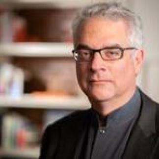 Portrait of Nicholas Christakis standing in front of a bookshelf