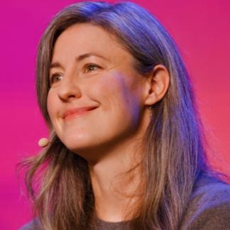 Portrait of Kathryn Paige Harden with a microphone, giving a talk
