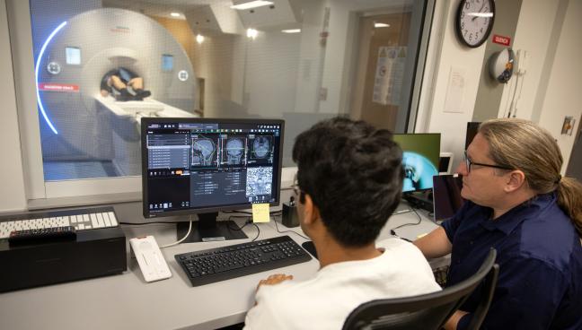 Photo of researchers looking at fMRI images on a computer screen 