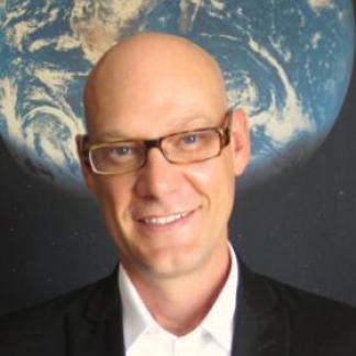 Portrait of Clayton Curtis smiling, with an image of a globe in the background