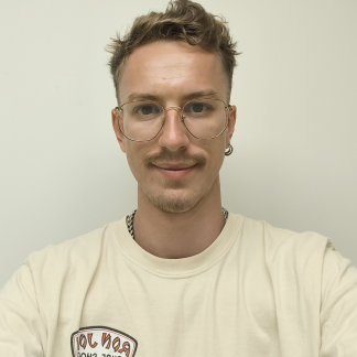 Portrait of Lucas smiling slightly in front of a white background