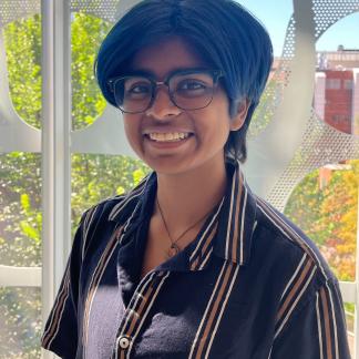 Portrait of Reyansh smiling in front of a window with trees in the background