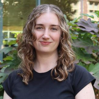 Portrait of Eva smiling in front of a natural background
