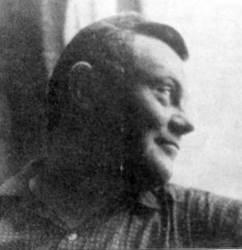 A black and white portrait of Bush looking out of a window and smiling.