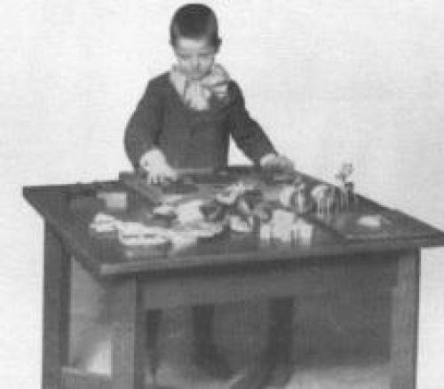 A black and white image of a child handling test materials used in the psychological clinic.